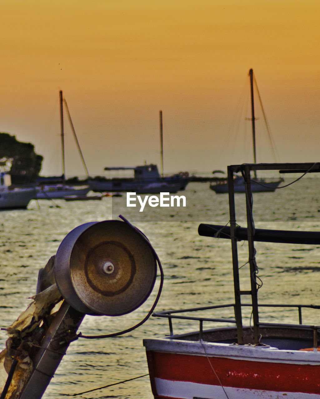 SAILBOATS MOORED IN SEA AGAINST SKY DURING SUNSET