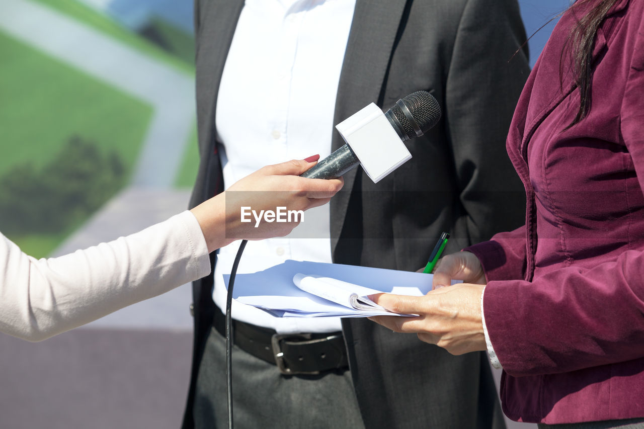 Cropped hand of journalist holding microphone during interview