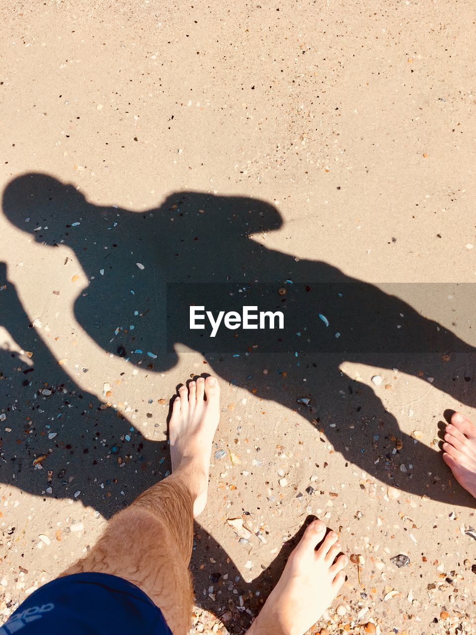 LOW SECTION OF PEOPLE STANDING ON SAND