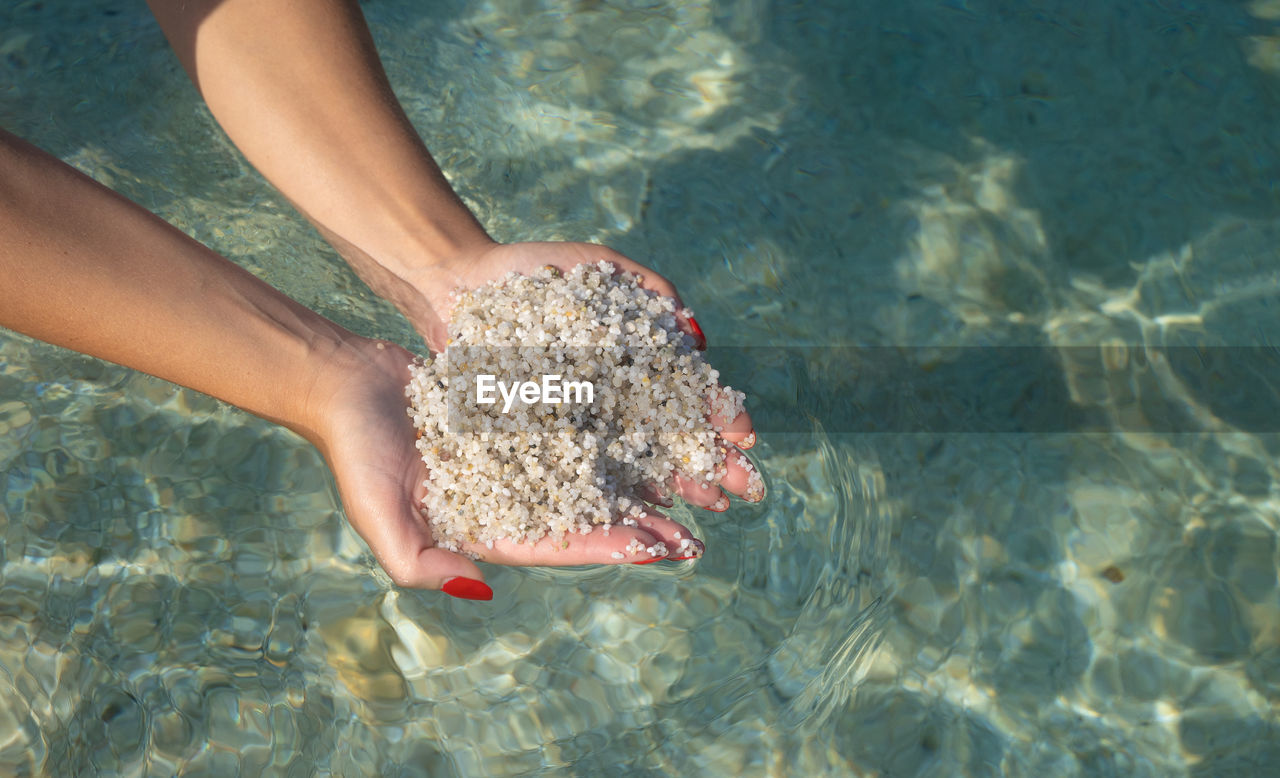 LOW SECTION OF WOMAN WALKING ON SEA SHORE