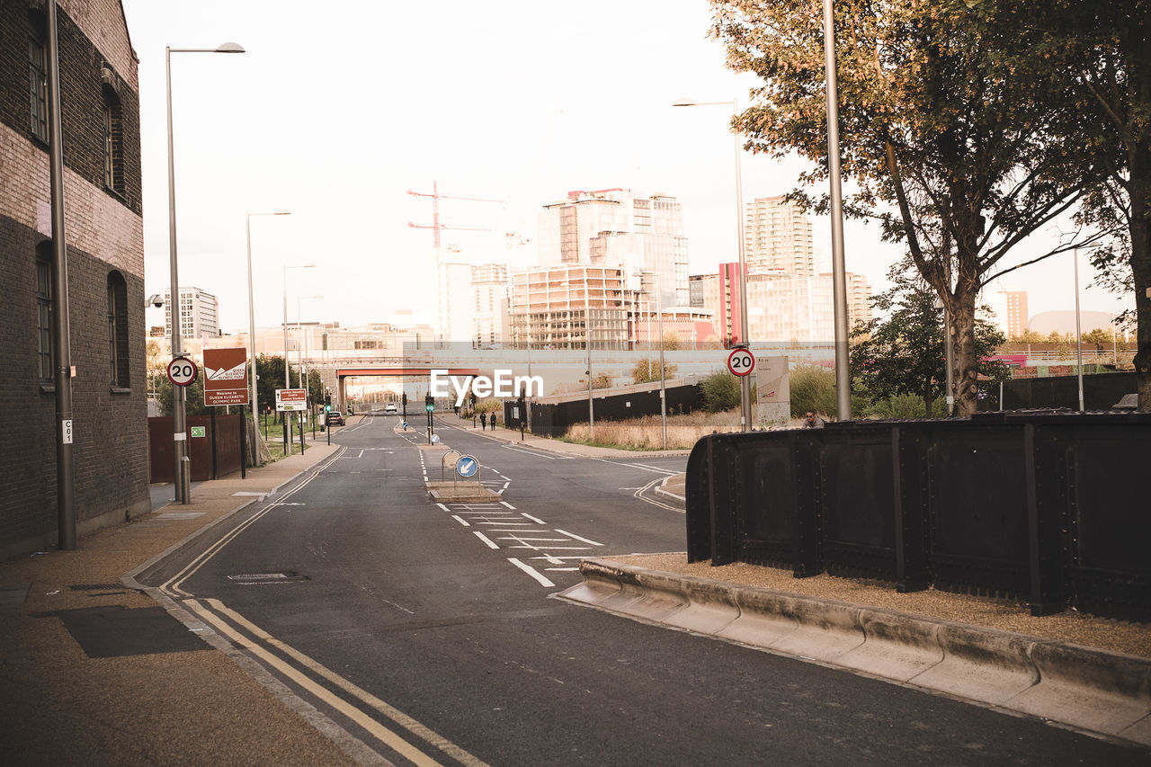 Road by buildings in city against sky