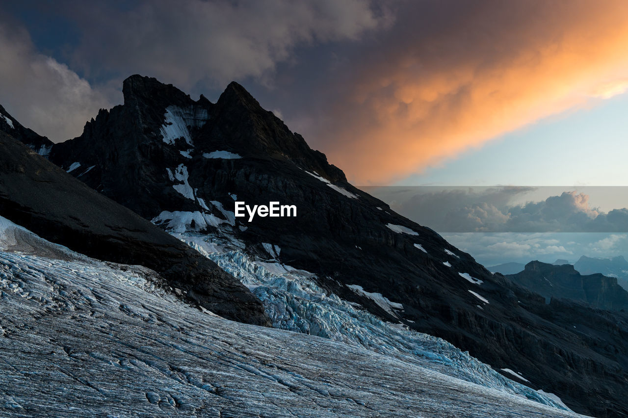 SCENIC VIEW OF SNOWCAPPED MOUNTAINS AGAINST SKY AT SUNSET