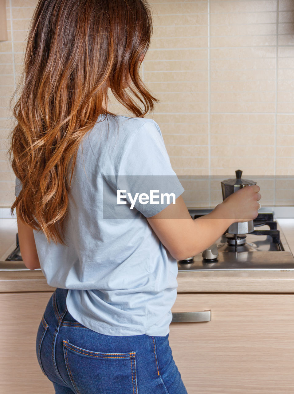 rear view of young woman washing hands while standing in sink