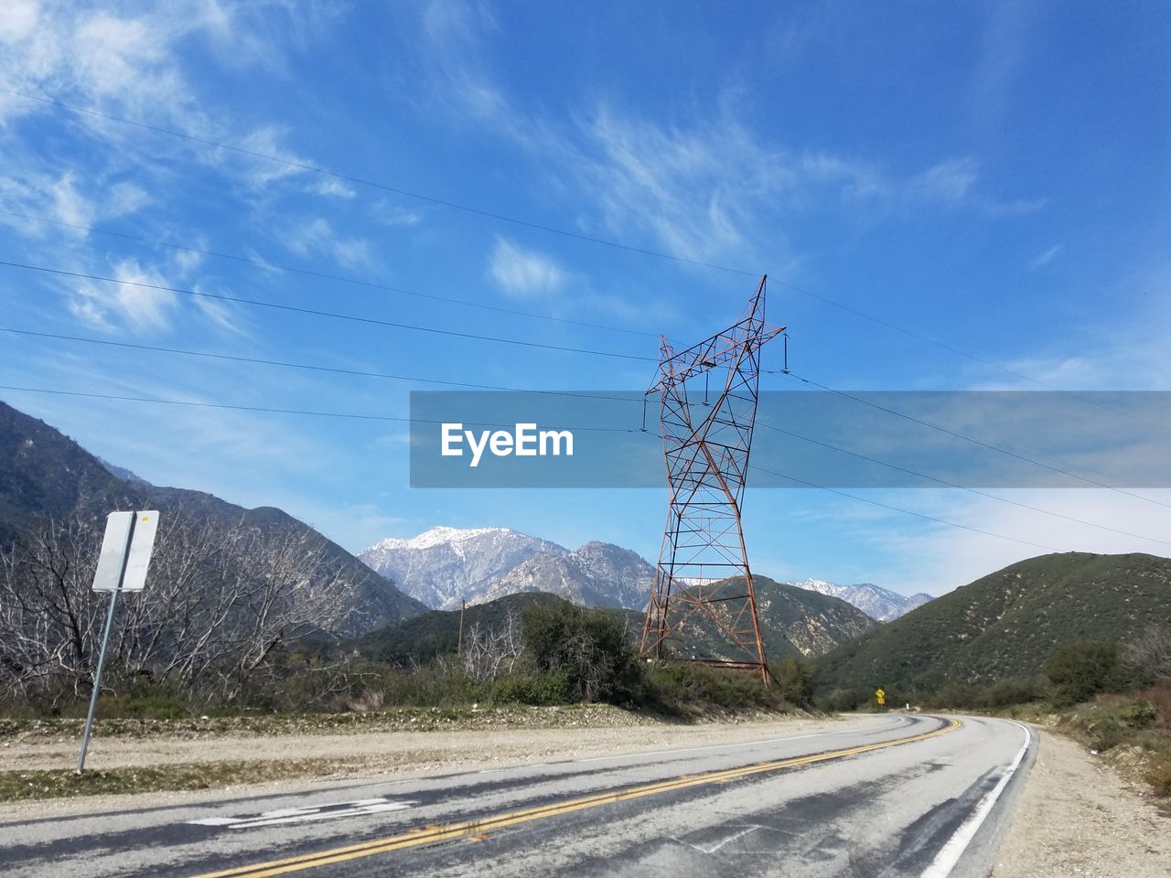 Electricity pylon by mountain against sky