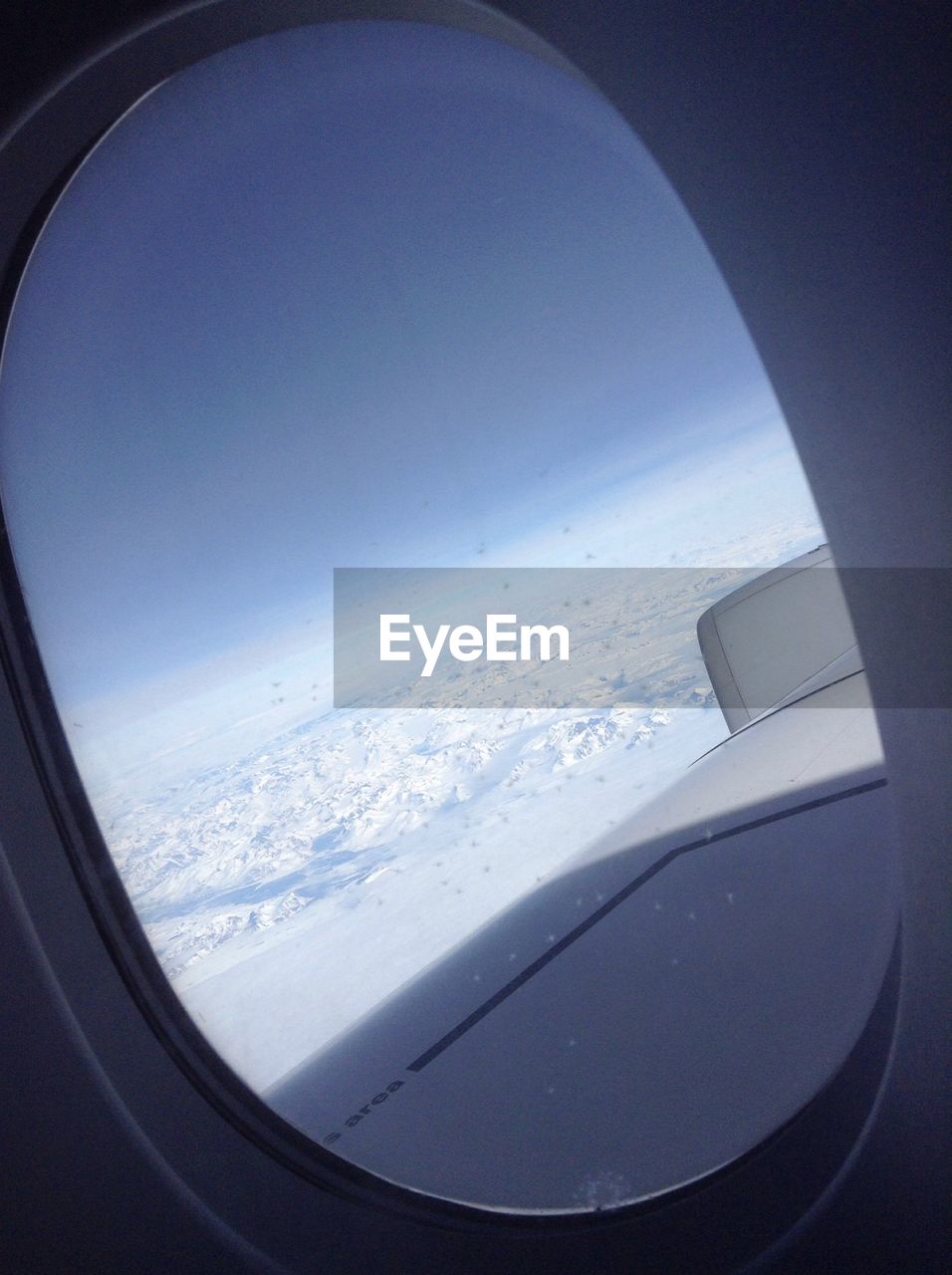 Snow covered landscape and sky seen through airplane window