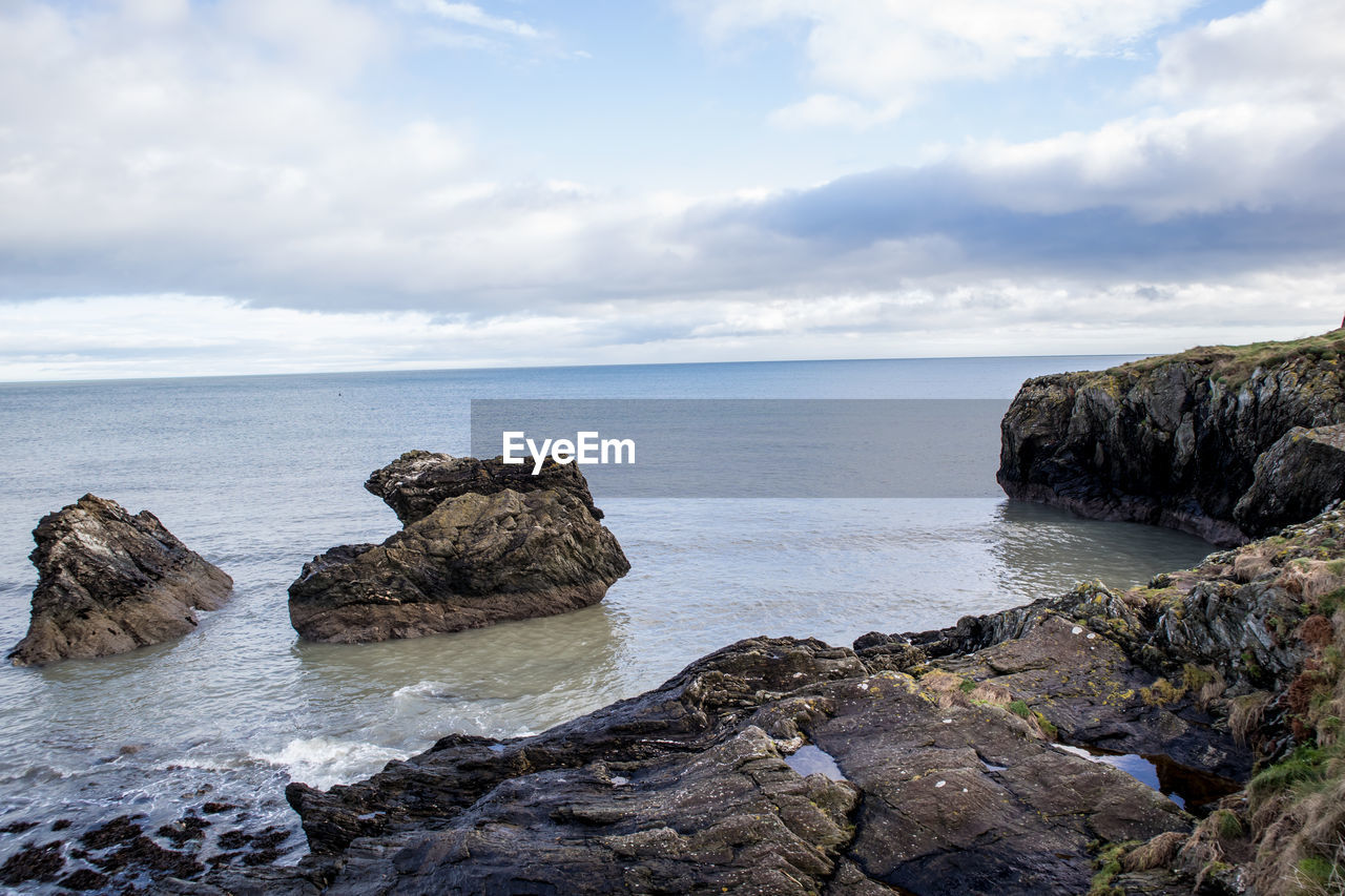 Scenic view of rocks in sea against sky