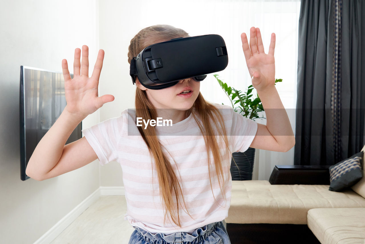 Girl wearing virtual reality simulator at home