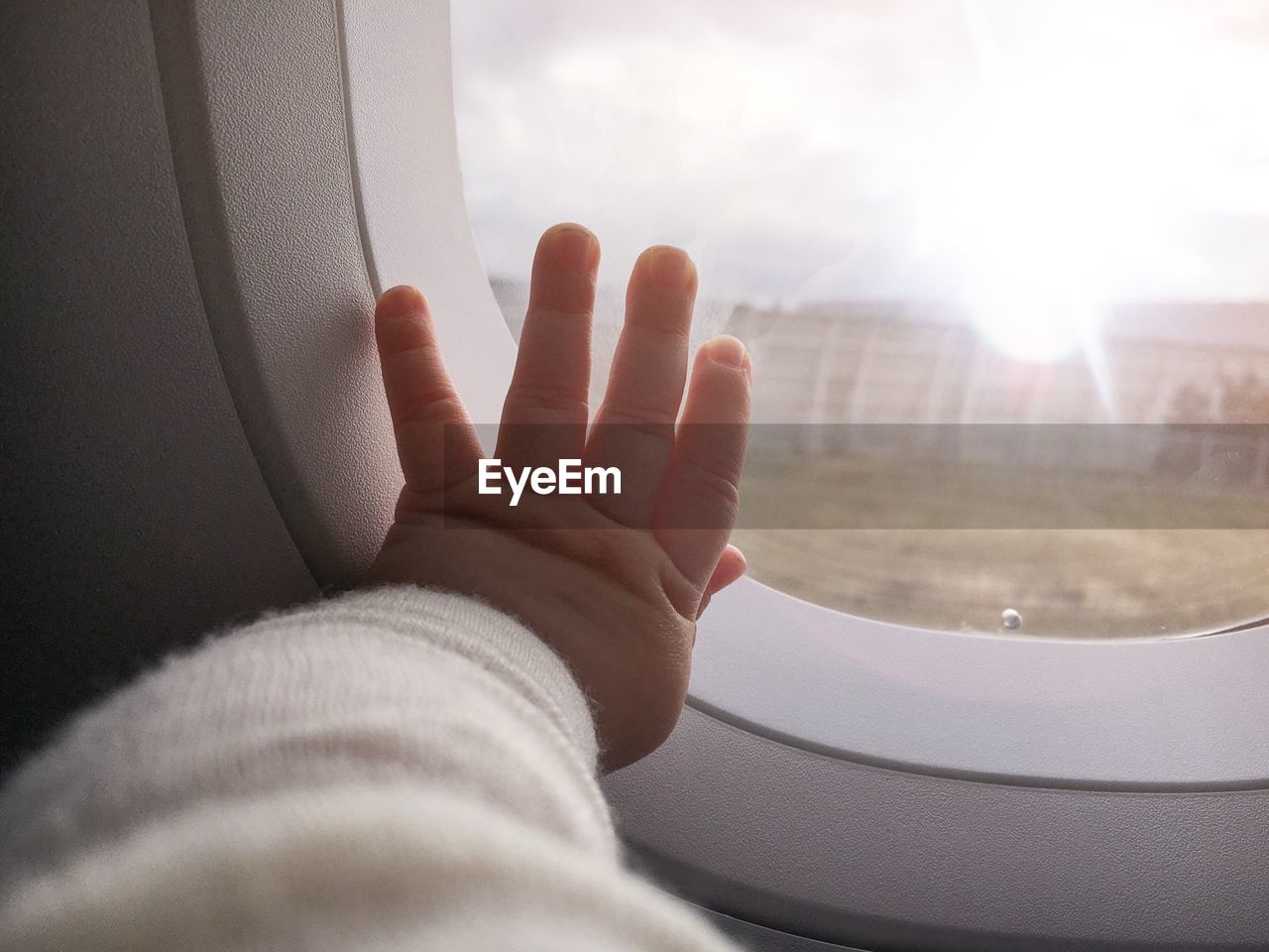 Cropped image of baby touching window in airplane