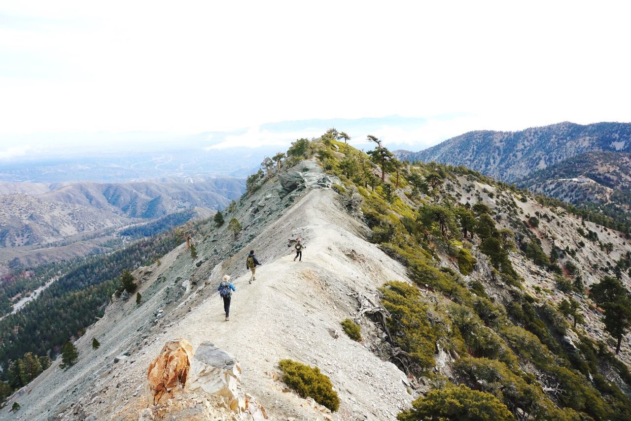 High angle view of people hiking on mountain against sky