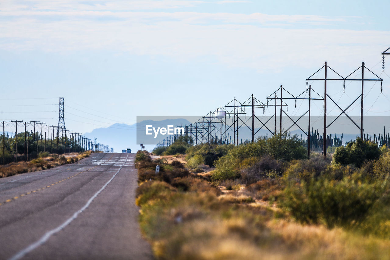 SURFACE LEVEL OF ROAD BY ELECTRICITY PYLONS AGAINST SKY