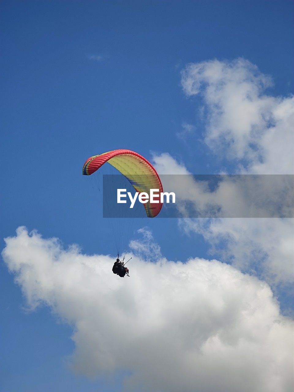 low angle view of person paragliding against cloudy sky