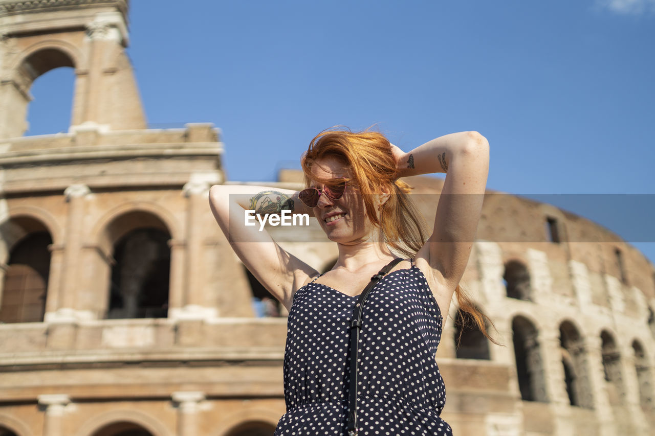 Stylish tourist doing hair near famous monument