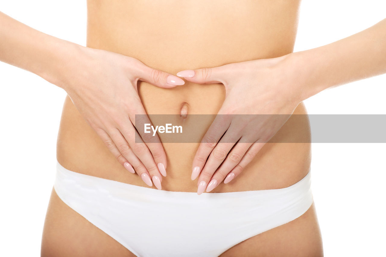 Midsection of woman touching stomach over white background