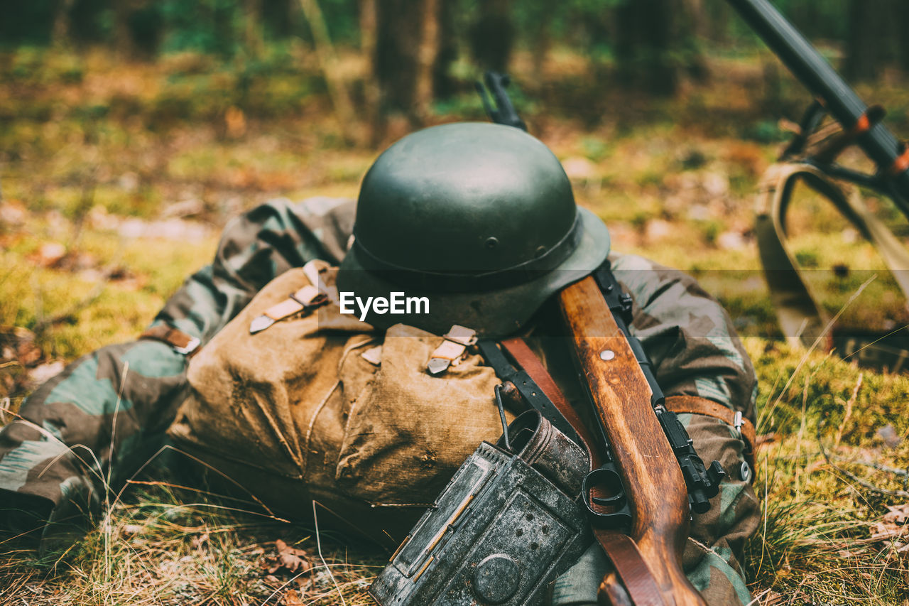 Close-up of army soldier with gun on grassy field