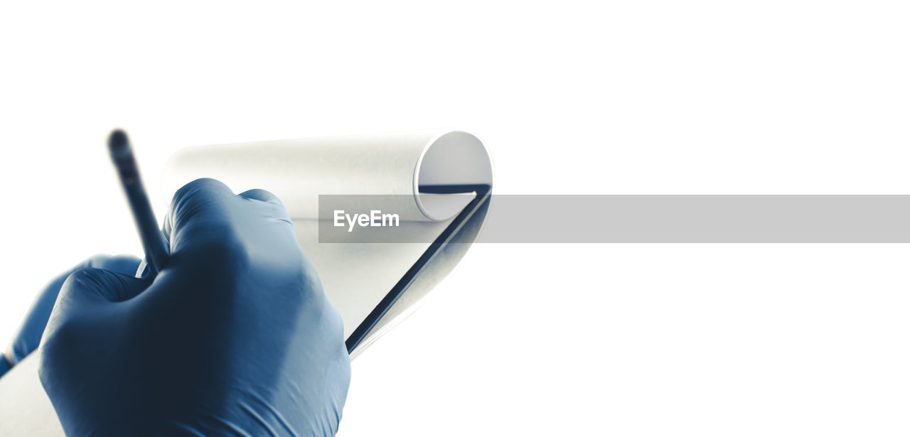 CLOSE-UP OF HAND HOLDING CAMERA AGAINST WHITE BACKGROUND