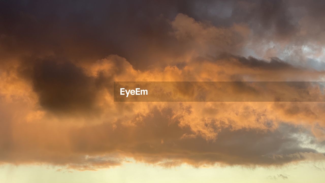 LOW ANGLE VIEW OF STORM CLOUDS AT SUNSET