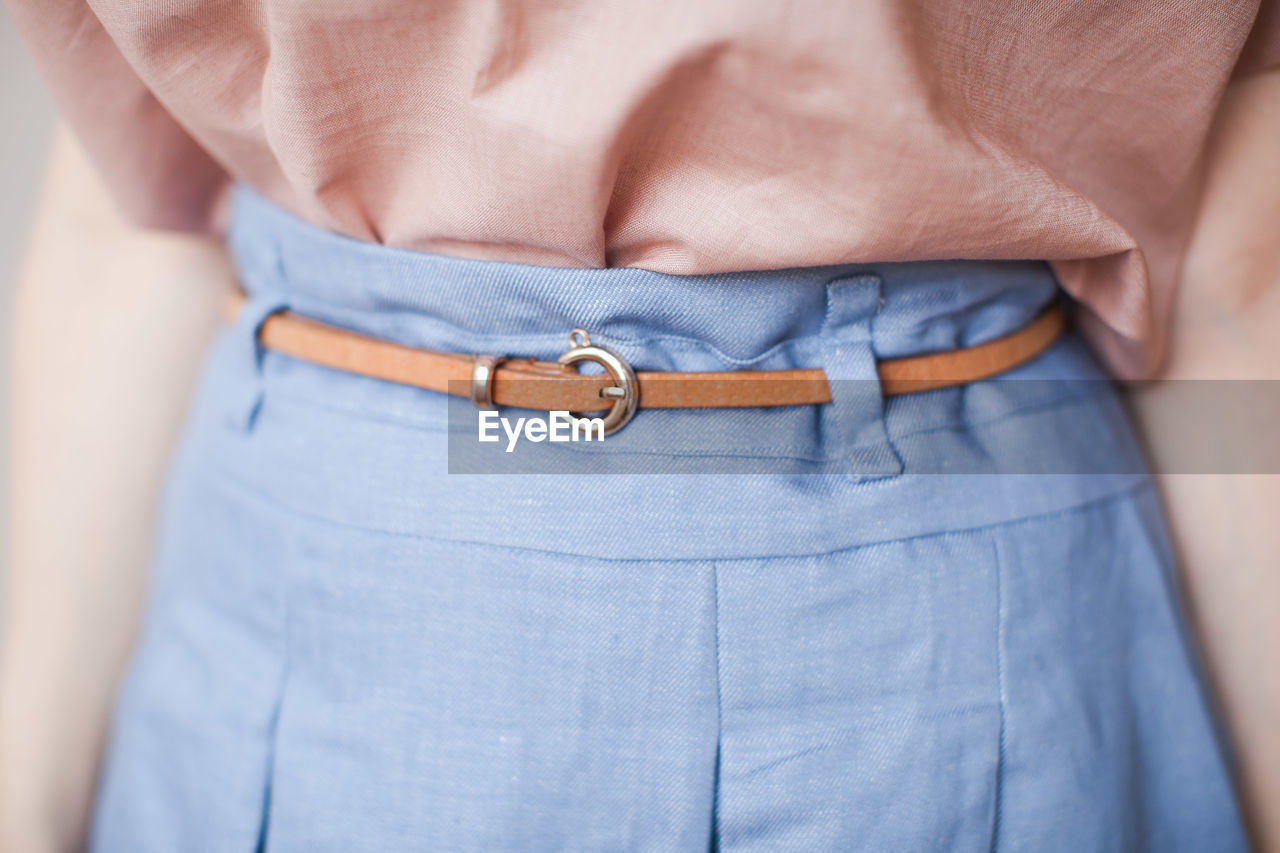 Midsection of woman wearing belt on blue skirt