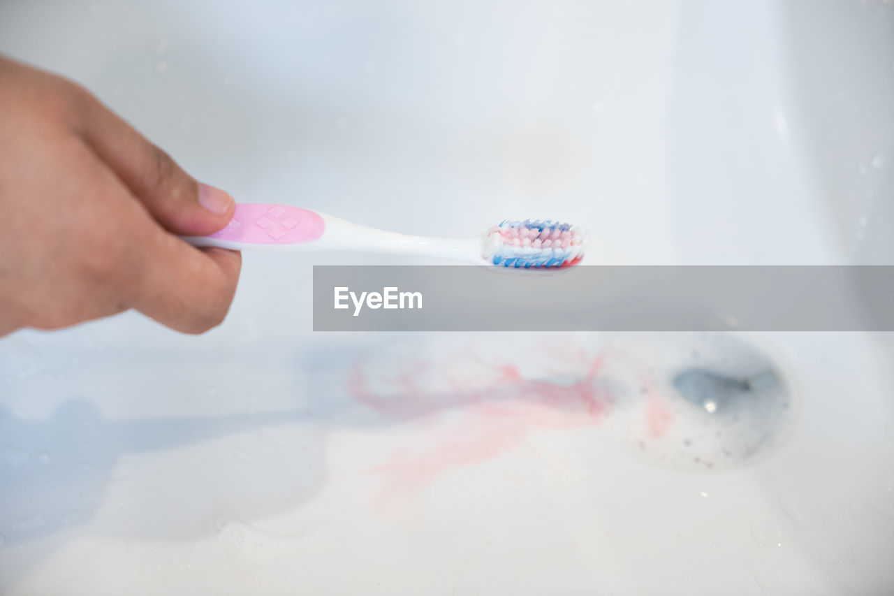 Close-up of hand holding toothbrush at sink