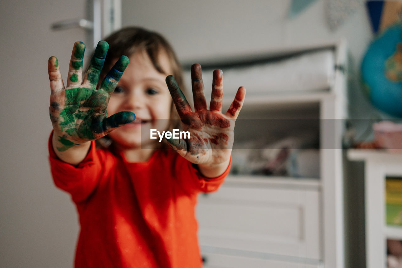 Portrait of girl showing messy hands at home