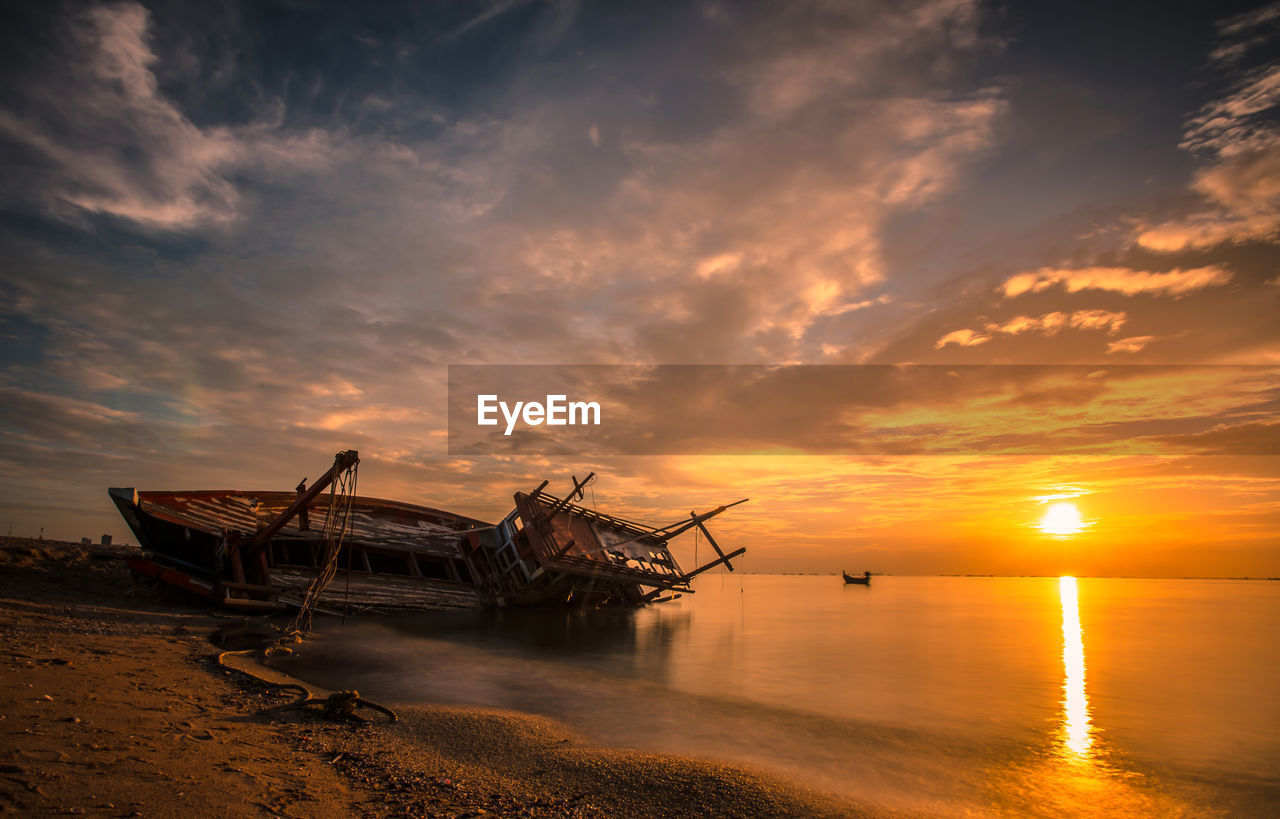 ABANDONED SHIP IN SEA AT SUNSET