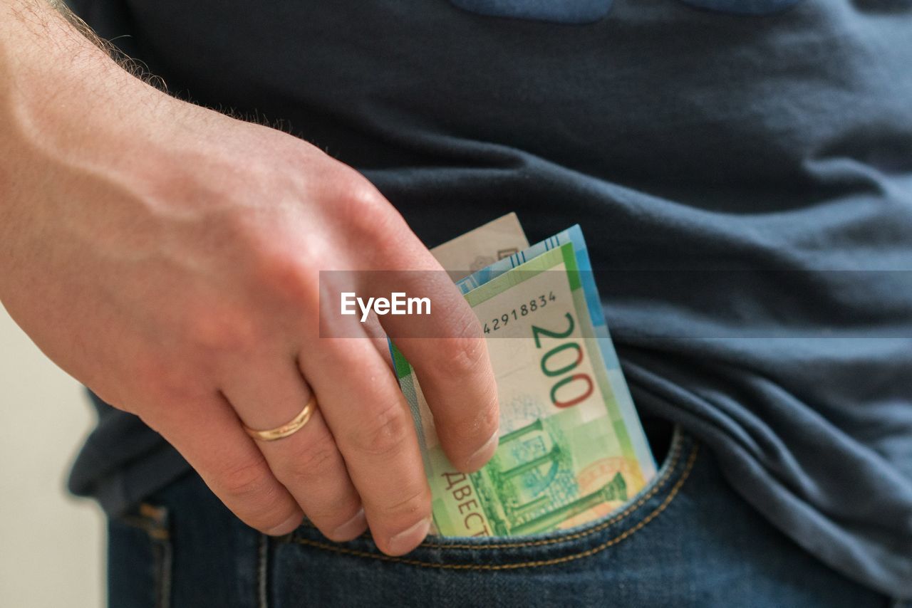 Midsection of man removing paper currencies from pocket