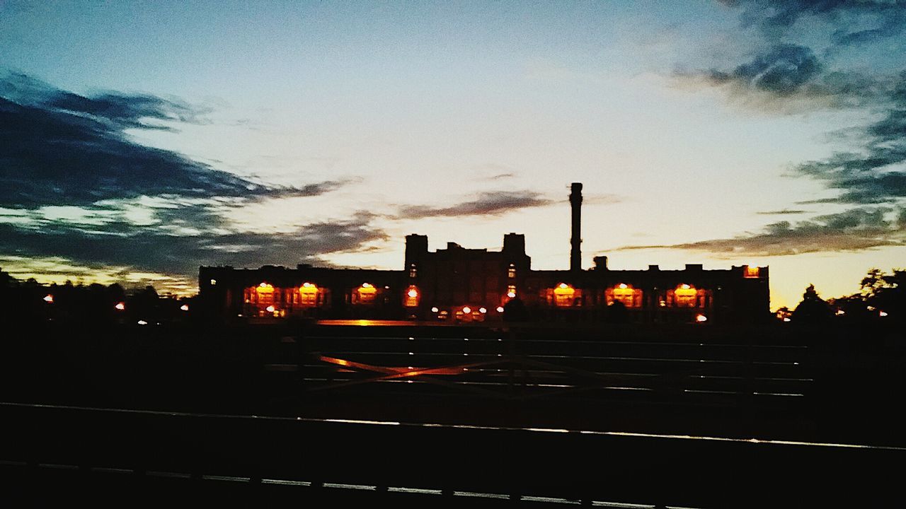 ILLUMINATED FACTORY AGAINST SKY AT SUNSET