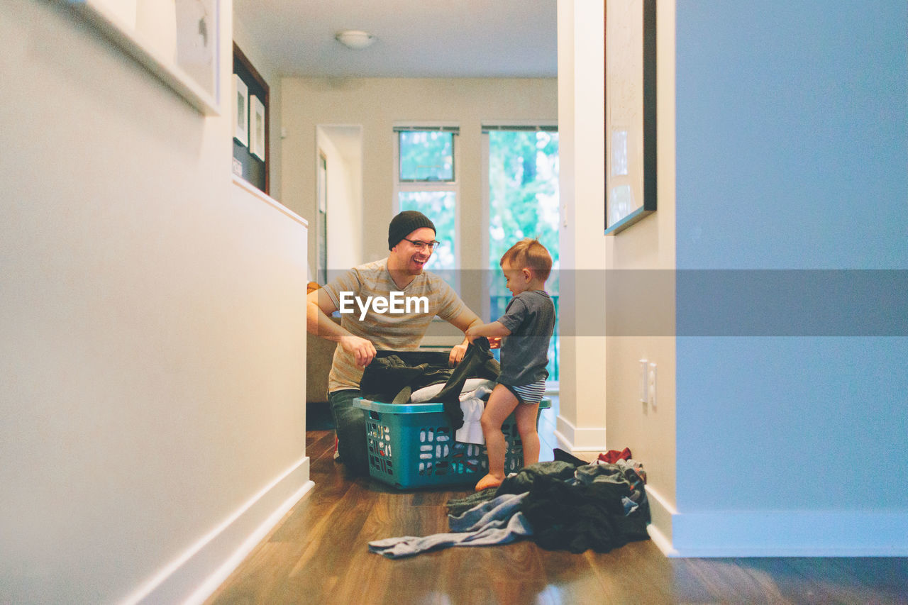 Father and son holding laundry at home