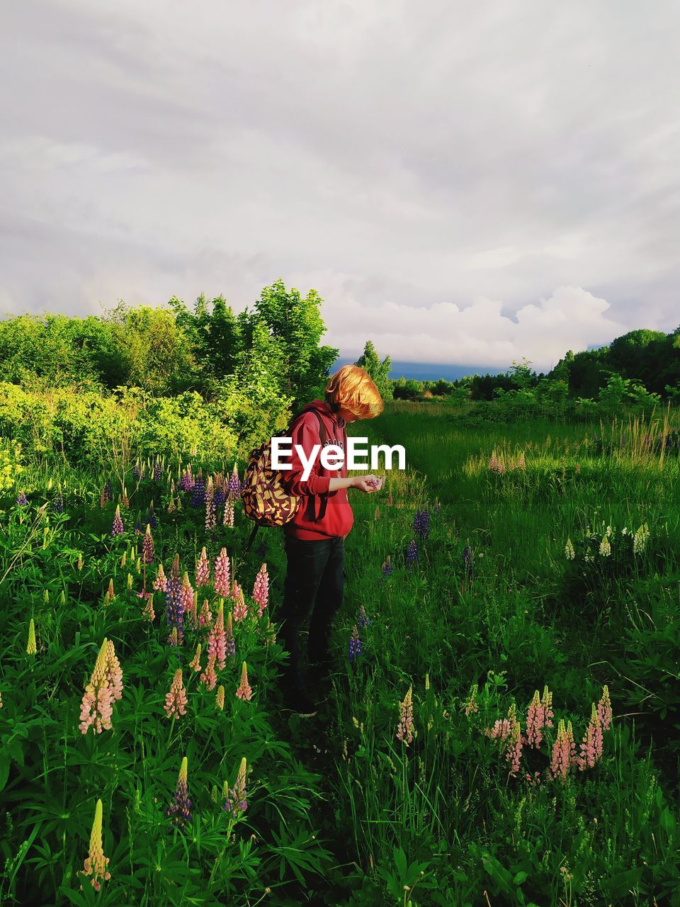 Boy standing on grassy land against sky