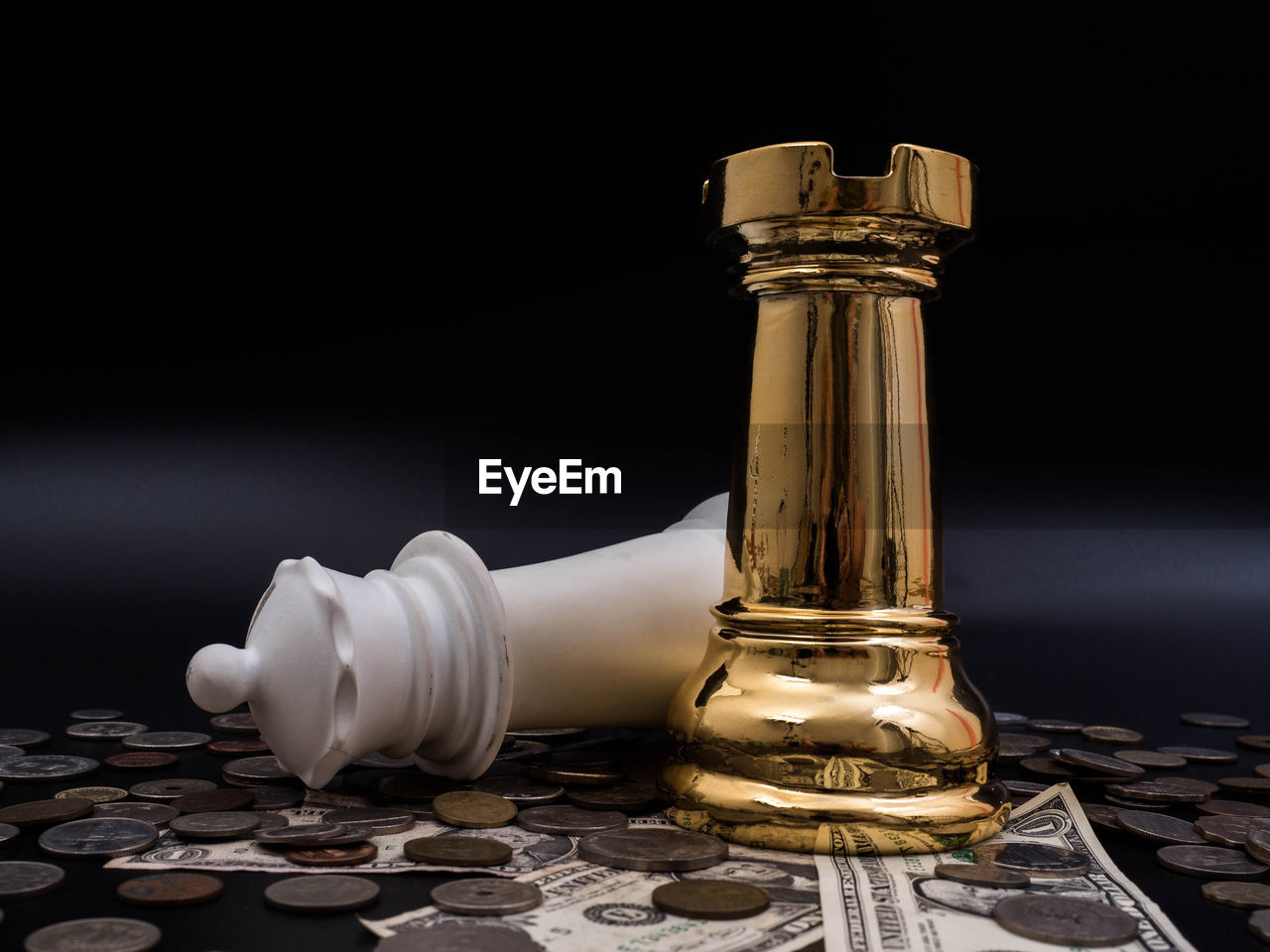 High angle view of chess pieces over coins and paper currency against black background