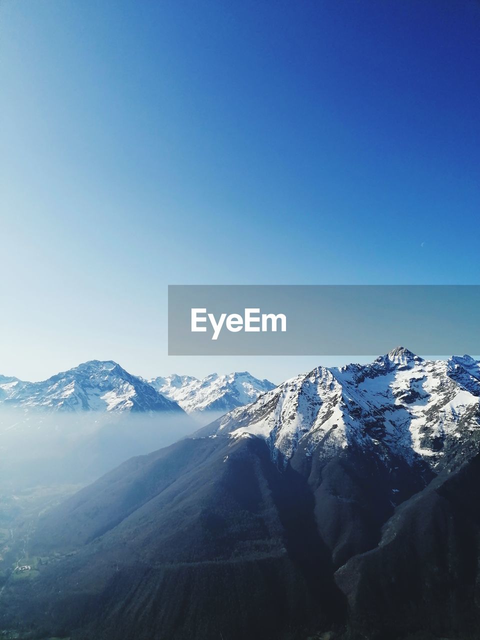 Scenic view of snowcapped mountains against clear blue sky