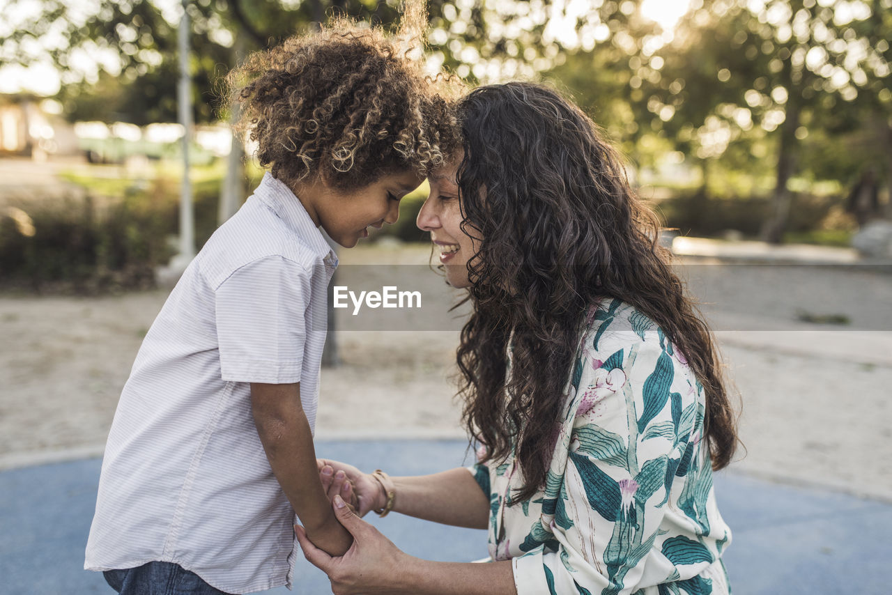 Side view of happy mother and son touching foreheads at park