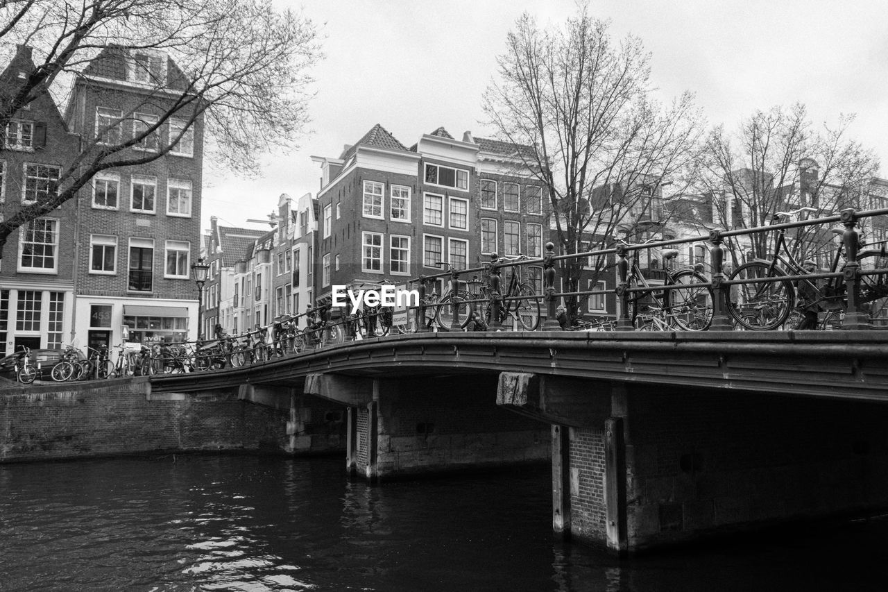 Bicycles parked on bridge over canal in city