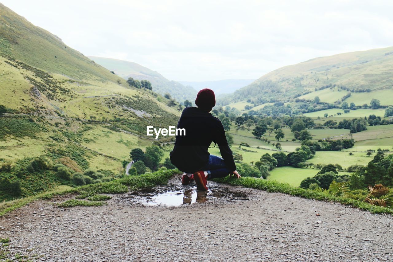 Rear view of man looking at mountains against sky