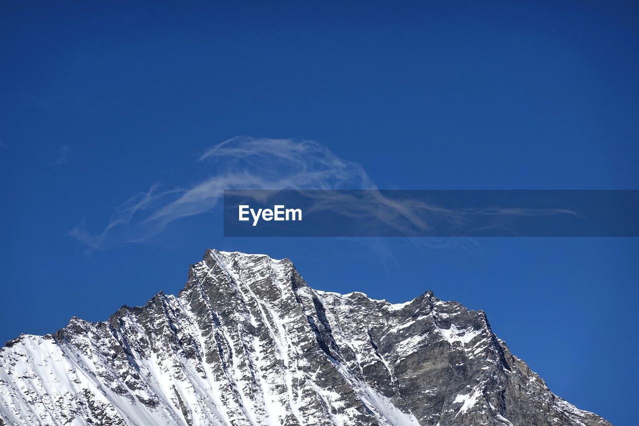 LOW ANGLE VIEW OF SNOWCAPPED MOUNTAIN AGAINST CLEAR BLUE SKY