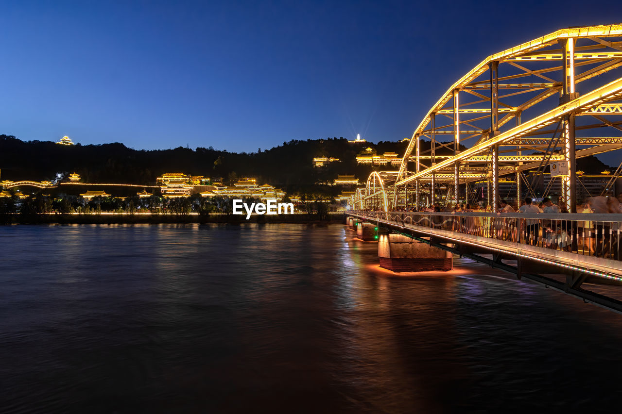 Illuminated bridge over river against sky at night in lanzhou