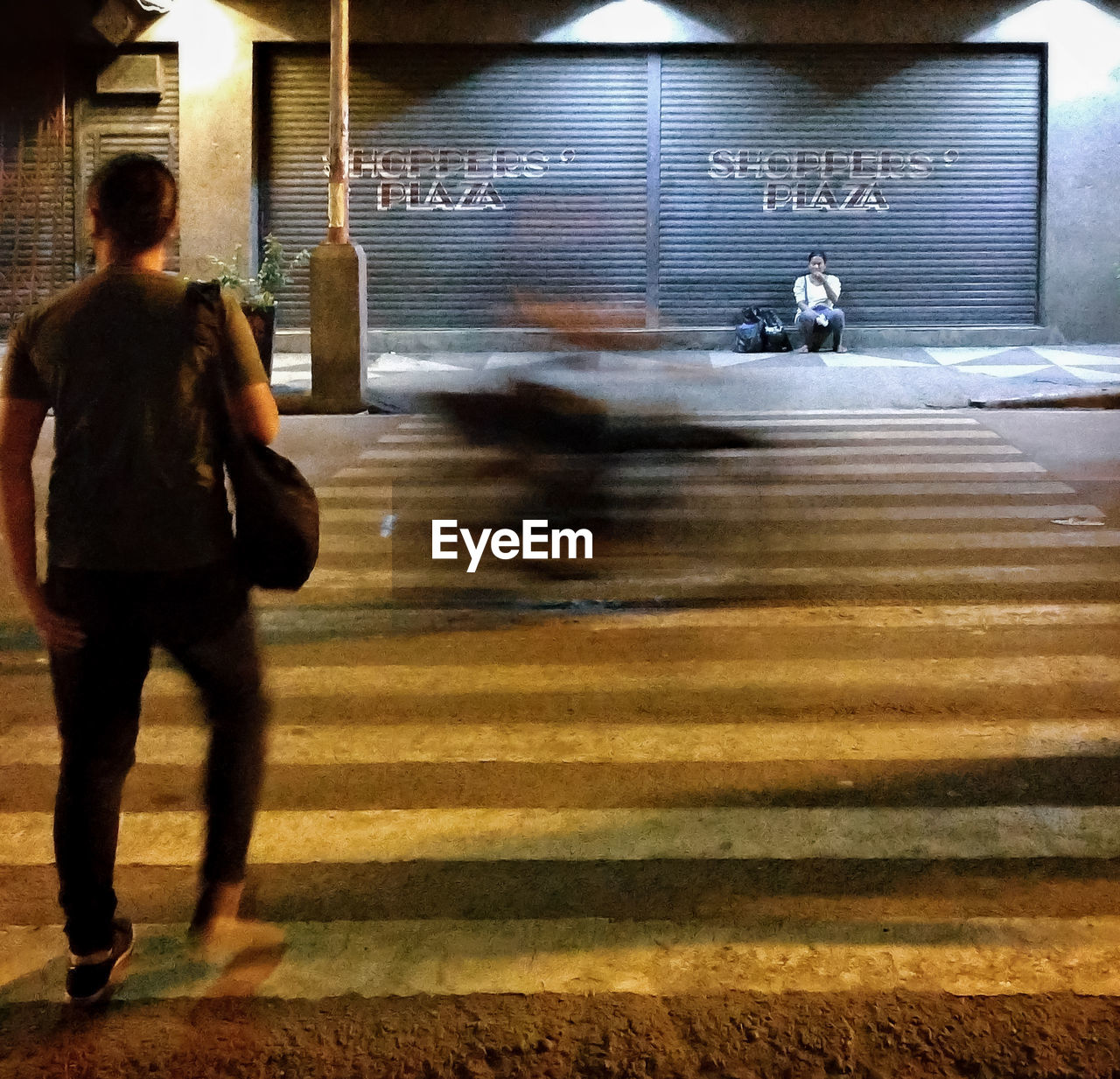 REAR VIEW OF A WOMAN WALKING ON CITY STREET