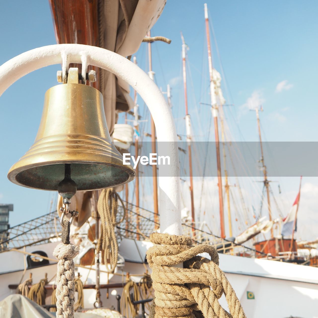 Low angle view of bells hanging on boat against sky during sunny day