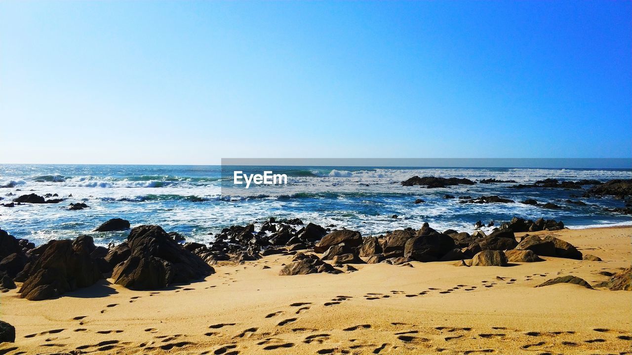 Scenic view of beach against clear blue sky