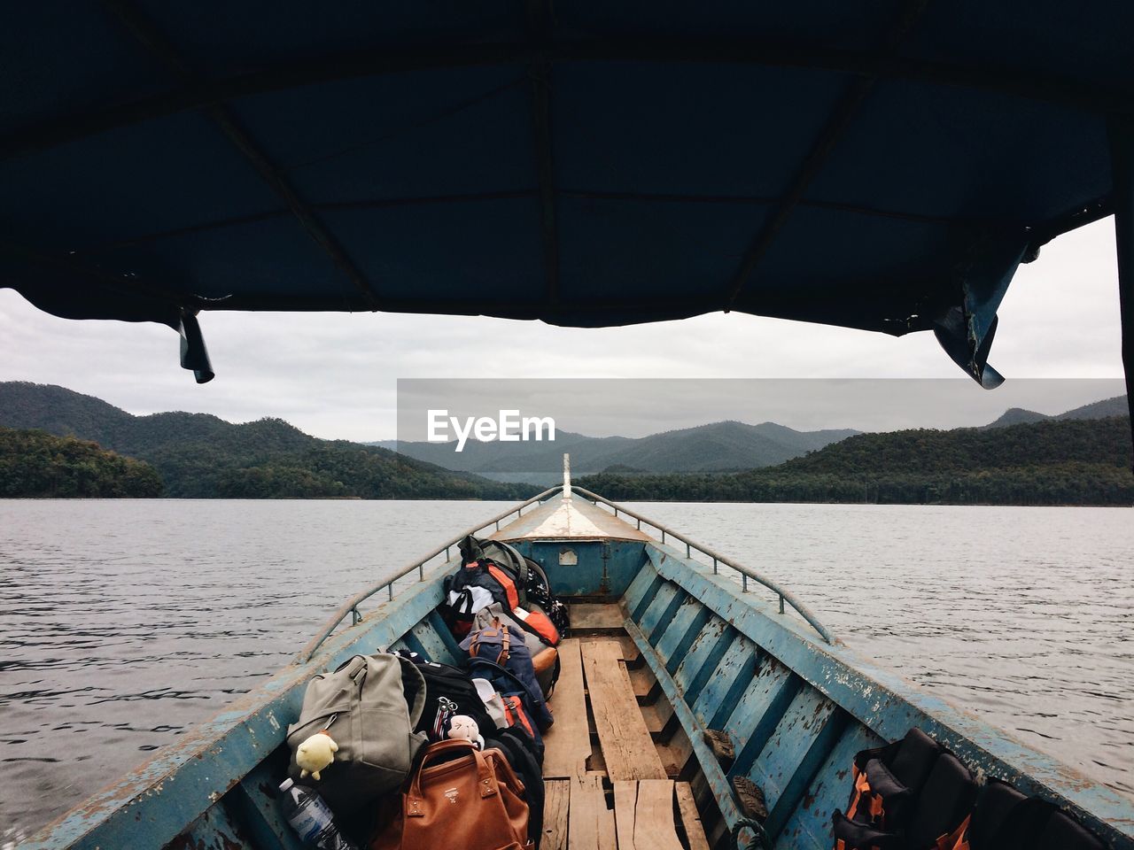 Bags in boat on river against cloudy sky