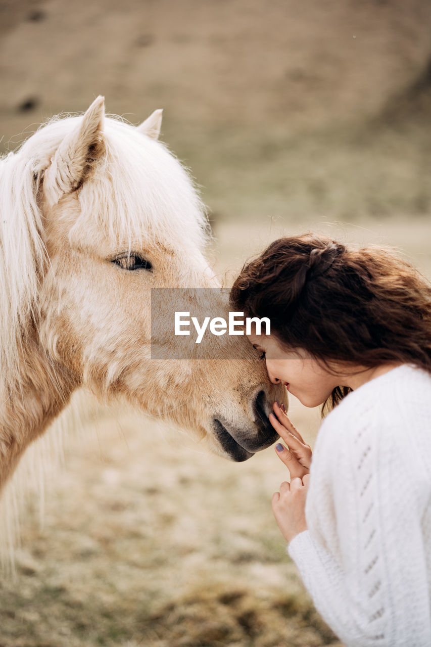 SIDE VIEW OF WOMAN WITH HORSE AT PARK