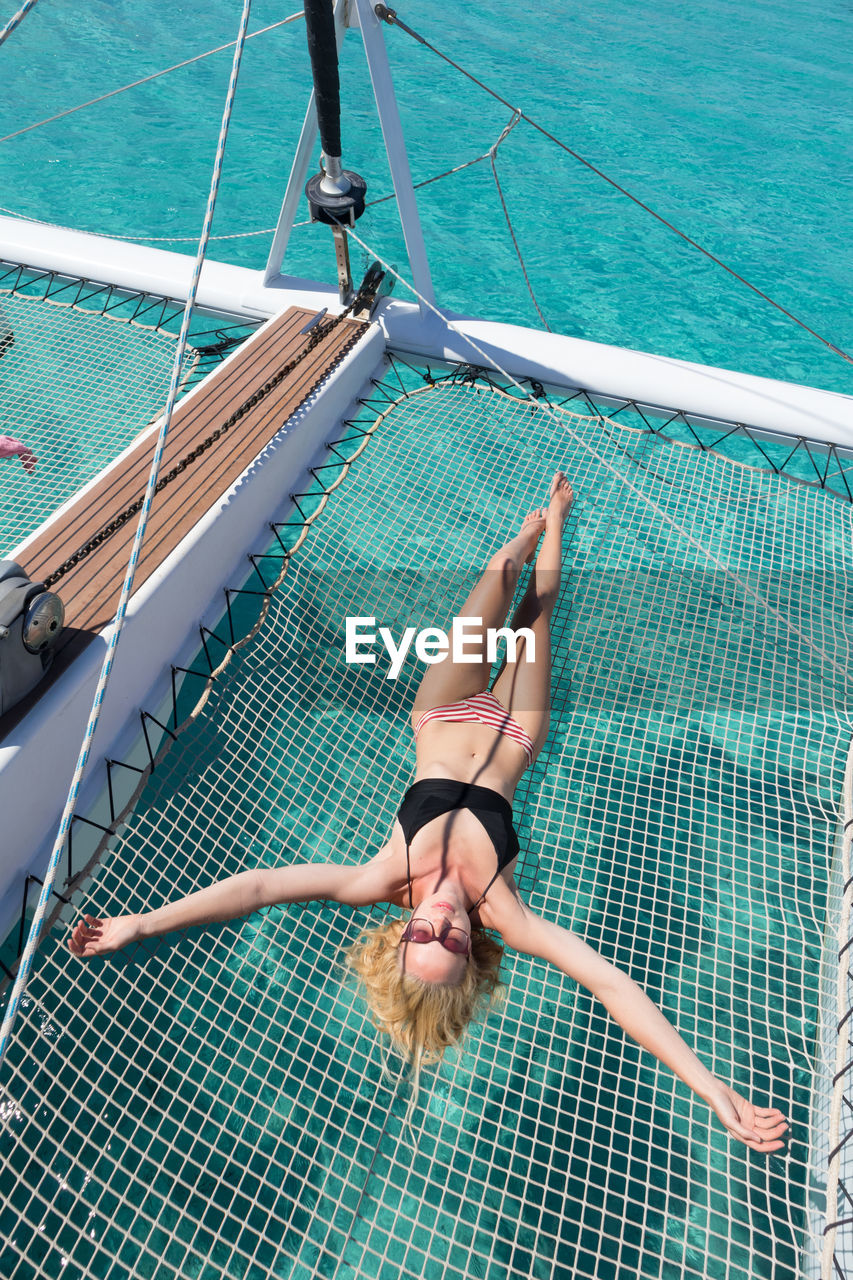High angle view of woman lying on net over sea