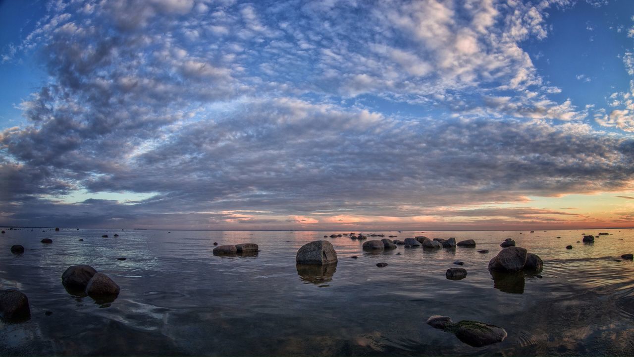 Rocks on sea against cloudy sky during sunset