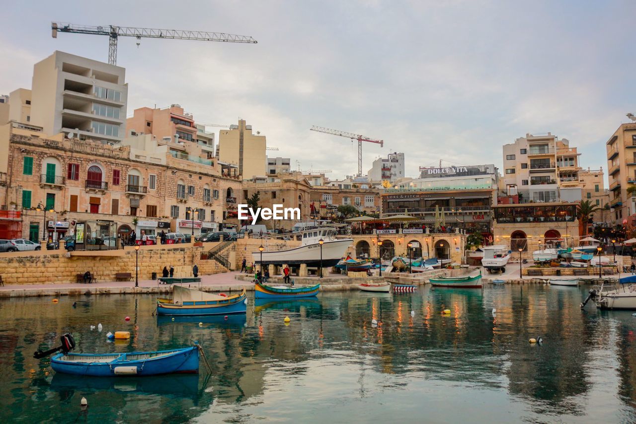 Boats moored in river against buildings in city