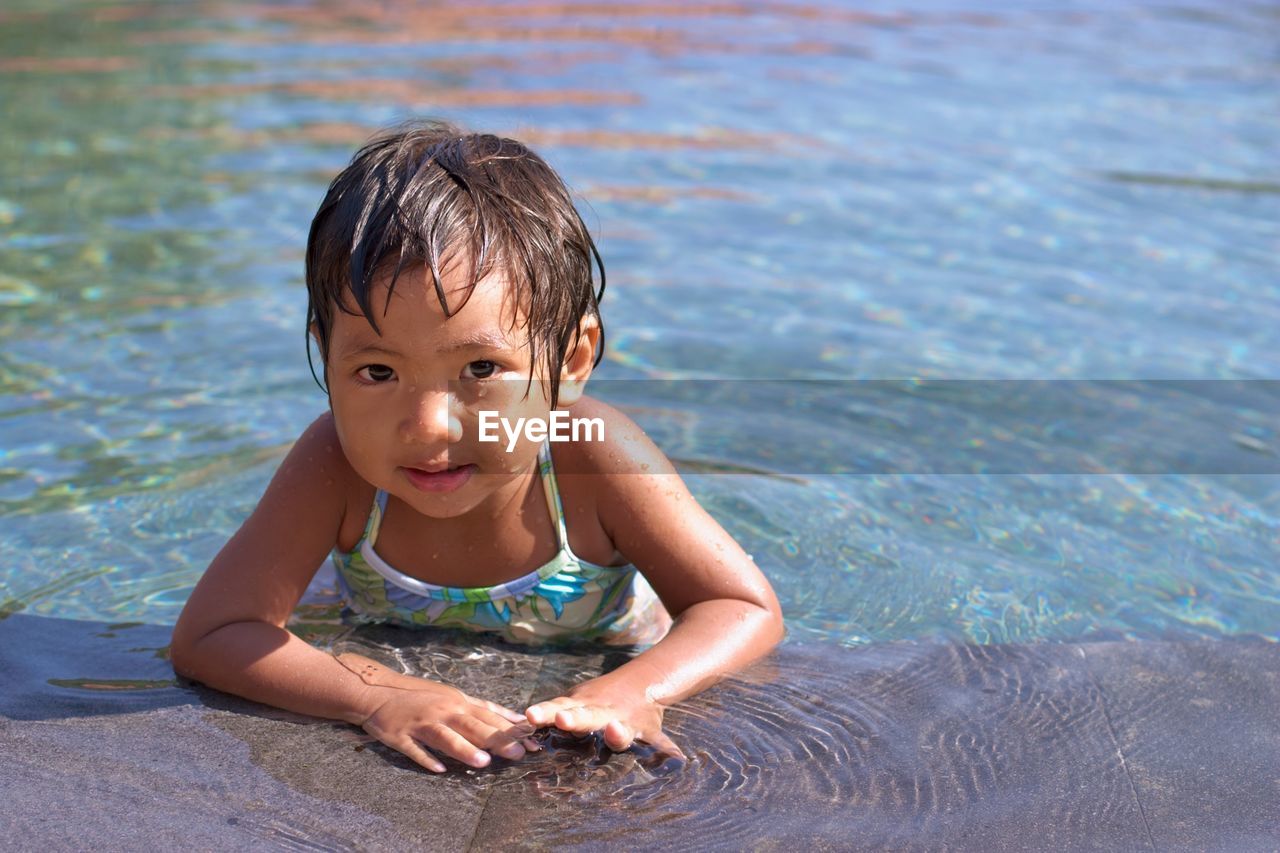 PORTRAIT OF CUTE BOY SWIMMING IN POOL