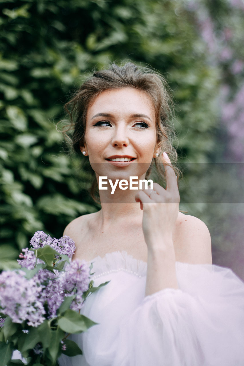 Beautiful bride in a wedding dress walks in a blooming apple-tree park in spring