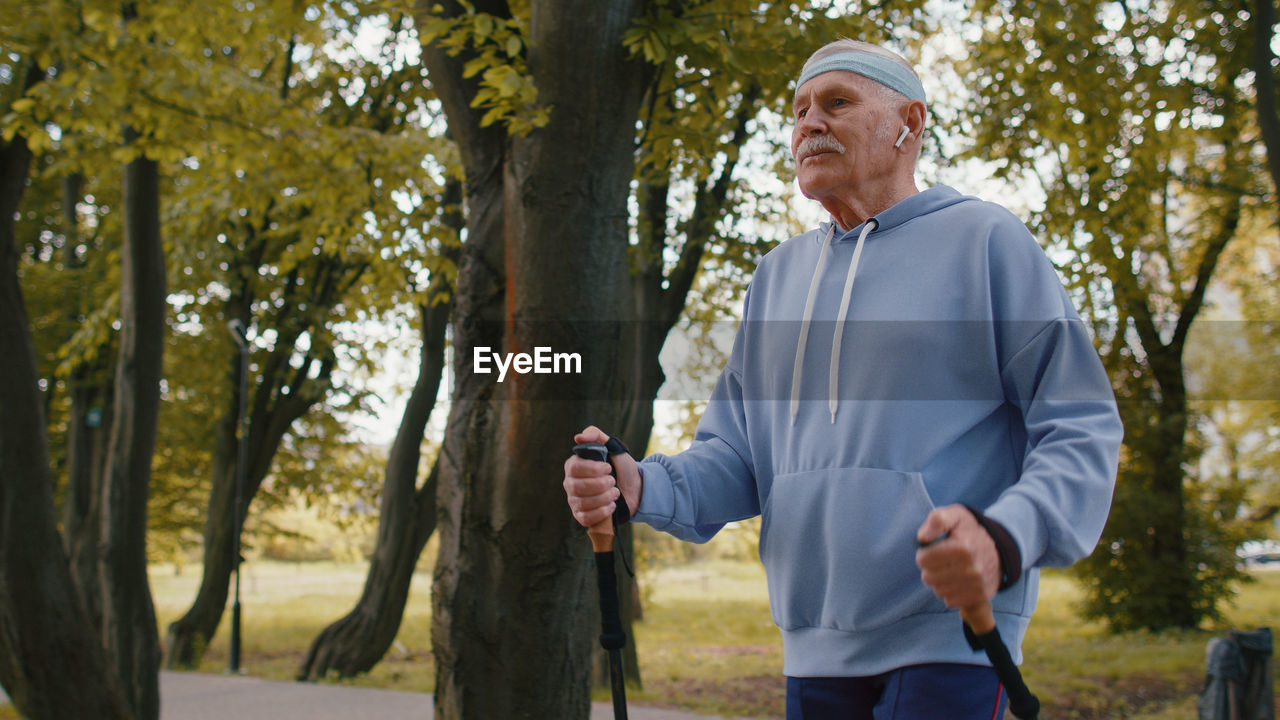 Senior man walking with nordic walking poles in park