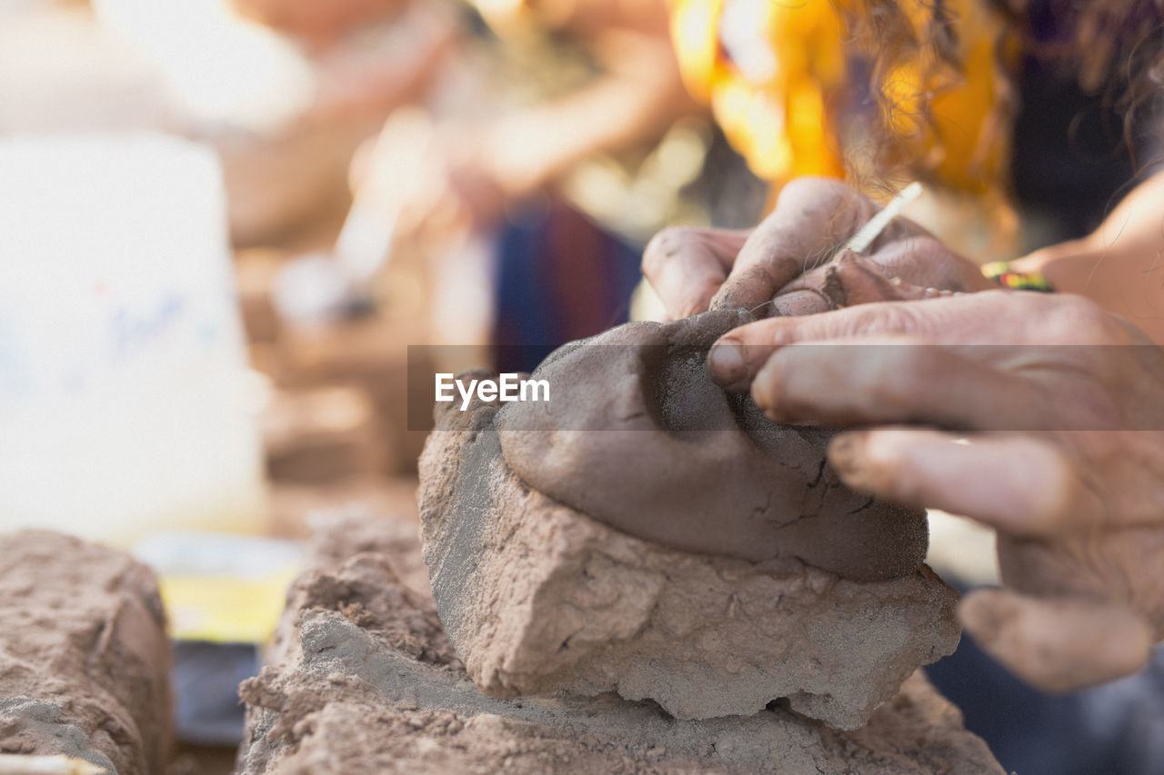 Cropped hands of woman mixing mud
