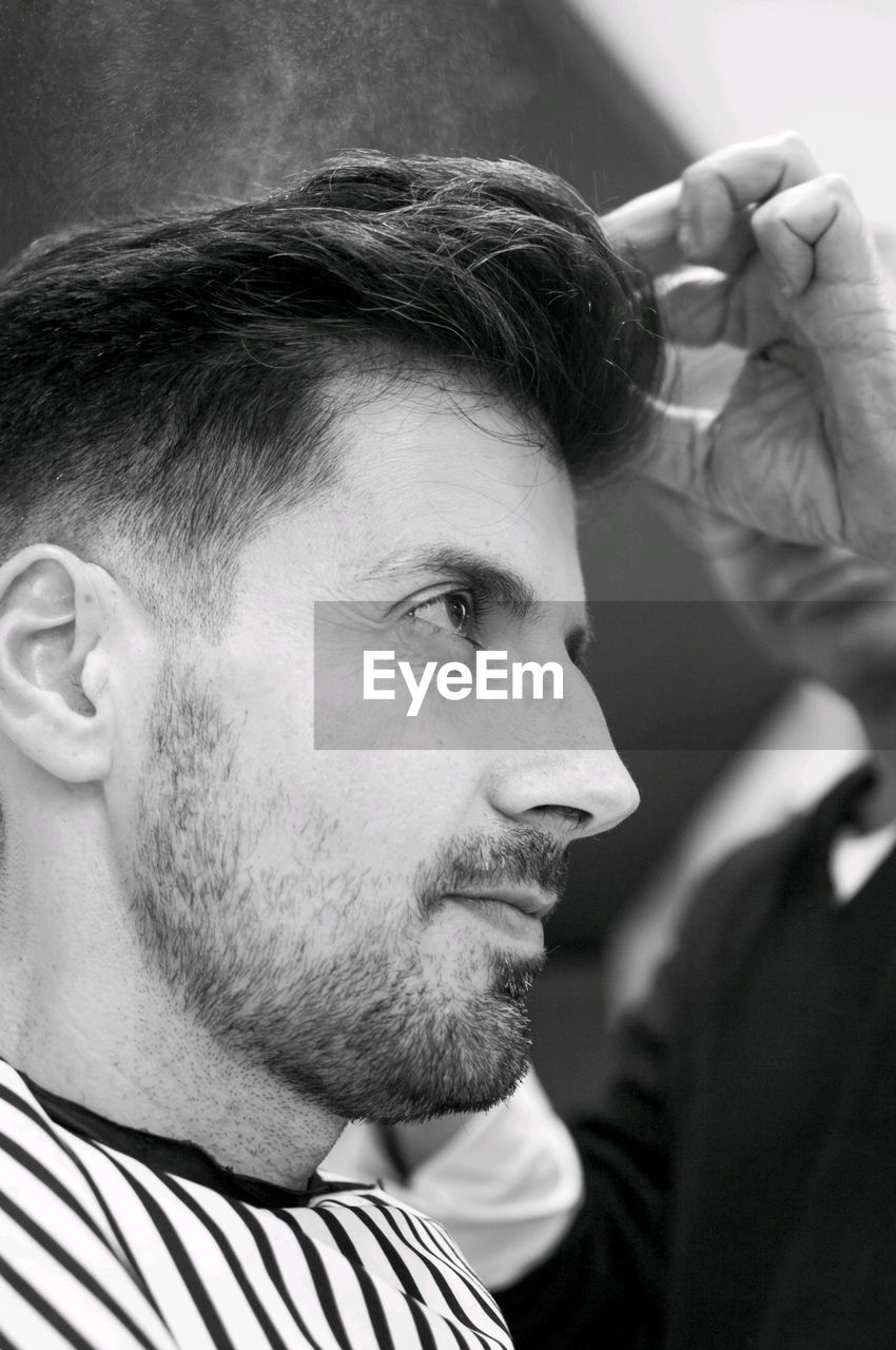 Side view of man and barber at salon