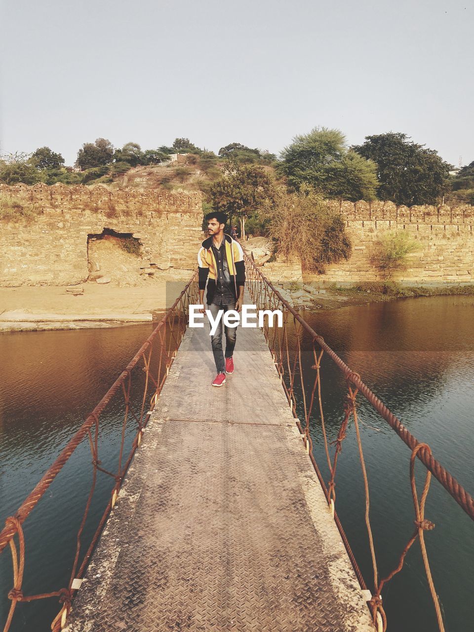 People standing on bridge against clear sky