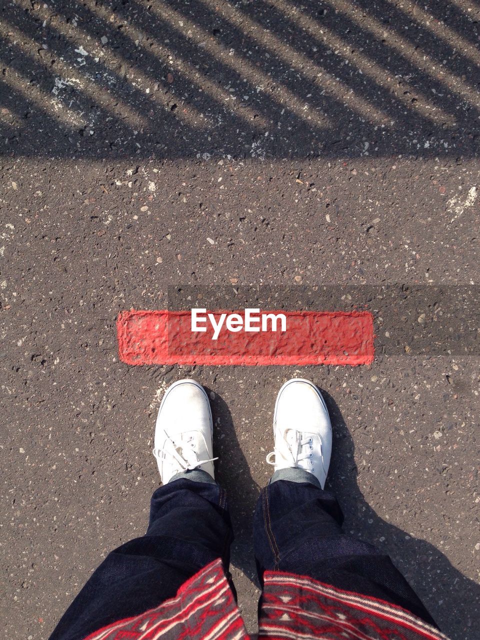 Low section of man standing in front of red line